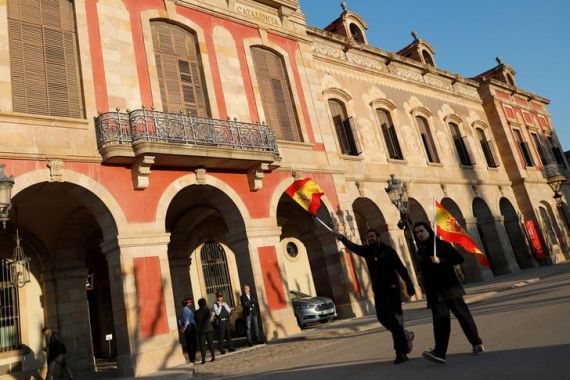 Two men hold Spanish flags while they walk past the parliament building in Barcelona