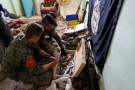 Fighters of Syrian Democratic Forces inspect weapons and munitions recovered at the former positions of the Islamic State militants inside a building at the frontline in Raqqa
