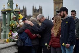 People embrace after laying flowers during an event to mark one week since a man drove his car into pedestrians on Westminster Bridge then stabbed a police officer in London