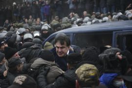 Georgian former President Mikheil Saakashvili struggles out of a police car in Kiev