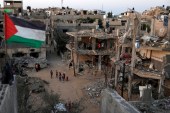 Palestinska zastava se vijori pored ruševina kuća uništenih u izraelskim zračnim napadima tokom nedavnog izraelskog napada na Gazu [Reuters/Mohammed Salem]