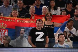 Muškarac u majici sa proruskim simbolom ‘Z’ na četvrtfinalu meča između Novaka Đokovića i Andreja Rubljova, pored navijača koji drže srpske zastave (AFP)