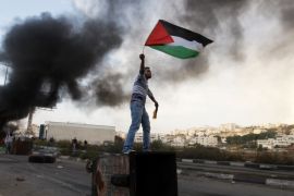 Palestinac maše državnom zastavom tokom protesta protiv izraelskih operacija u Pojasu Gaze, ispred Ofera, izraelskog vojnog zatvora smještenog u blizini grada Ramallaha na Zapadnoj obali (AP)