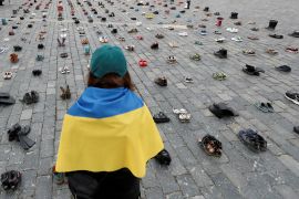 Žena gleda obuću koja simbolizira ratne zločine nad Ukrajincima (Reuters)