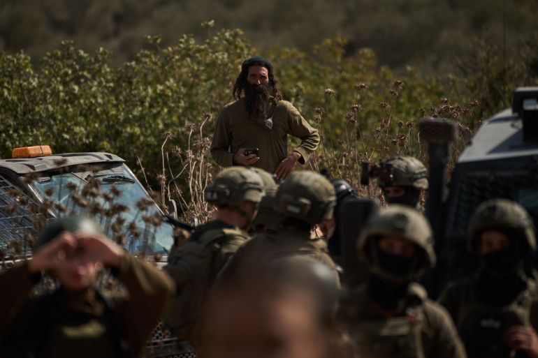 Izraelski doseljenik posmatra blokadu izraelskih snaga na okupiranoj Zapadnoj obali, gdje su Palestinci spriječeni da beru masline (Leo Correa/AP Photo)